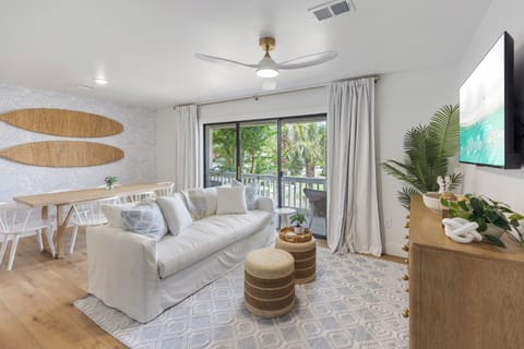 Sink into plush seating in your airy living space, where natural light pours through glass doors opening to your private balcony with lush tropical views.