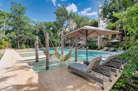 Pool deck with lounge chairs, hammocks, and shaded palapa seating.