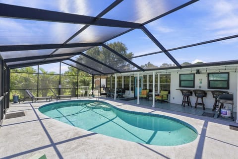 Private screened pool with covered patio, bar seating, and grill