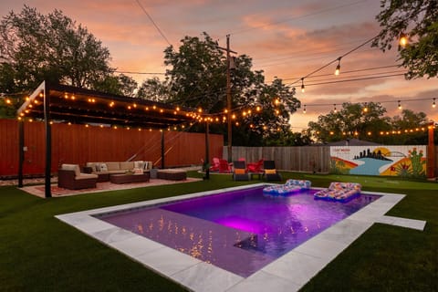 💜 As the sun sets, the pool glows and string lights twinkle overhead. Float the night away, lounge under the pergola, or sink a putt on the green. 🌅✨ The "Stay Weird" mural sets the scene for unforgettable Austin nights at SoCo Oasis. 🌴