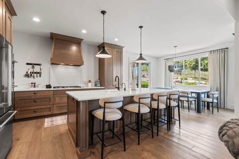Gather around the spacious main level kitchen island with warm wood tones, modern appliances, and natural light flowing in from your backyard. Perfect for cooking together and making memories.