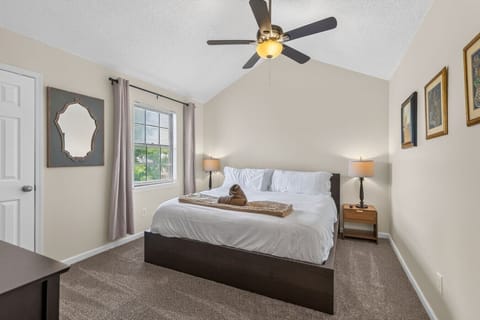 Spacious primary bedroom with a king bed, vaulted ceiling, ceiling fan, and warm bedside lighting.