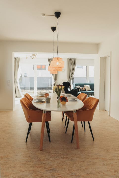 Sunny dining for six with woven pendants and wall-to-wall windows