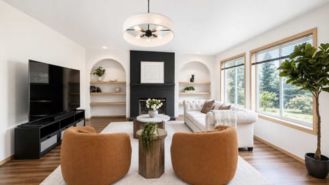 Gather in a beautifully styled, sun-drenched living room complete with a sleek fireplace setup and elegant built-in shelving.