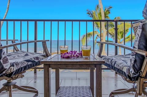 Comfortable balcony seating area with two armchairs and a table overlooking the ocean. 🌴