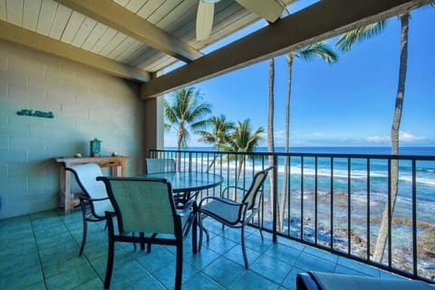Outdoor balcony dining table setup with beautiful ocean and palm tree views at twilight