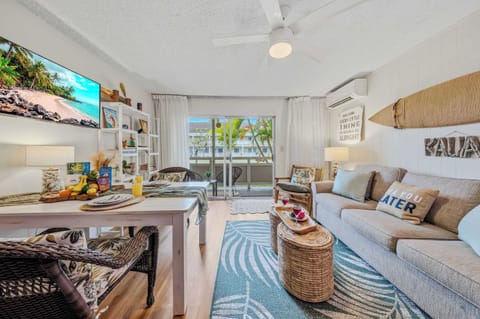 Bright living room with plush sofa, TV, surfboard decor & patio access