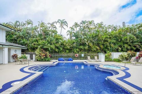 Relaxing outdoor swimming pool surrounded by tropical palm trees and lounge seating