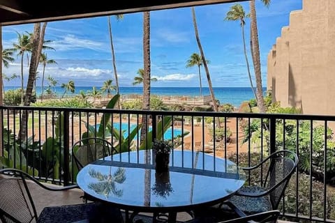 Balcony dining area overlooks tropical gardens, blue water, and scenic coastline