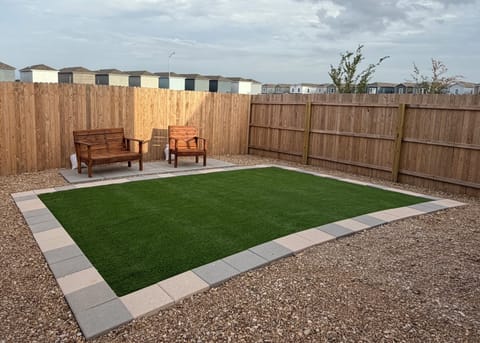 Relax in our private backyard with cozy patio seating, turf, and shade.