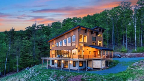Modern mountain retreat with glowing sunset views, expansive decks, and a peaceful wooded backdrop.