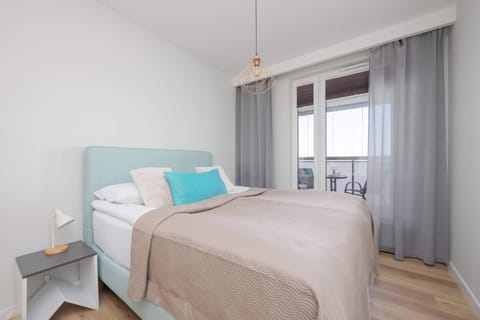 Comfortable bedroom with a cozy double bed, soft bedding and floor-to-ceiling windows bringing in plenty of natural light.