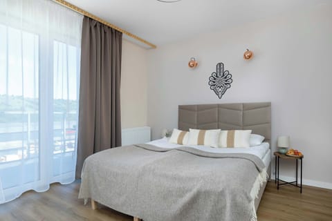 Bright studio apartment with a comfortable double bed, large windows, and modern décor.