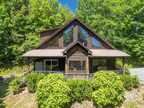 Front Facade — Full View - Straight-on shot of the cabin's A-frame gable, expansive windows, and deck with a hot tub.