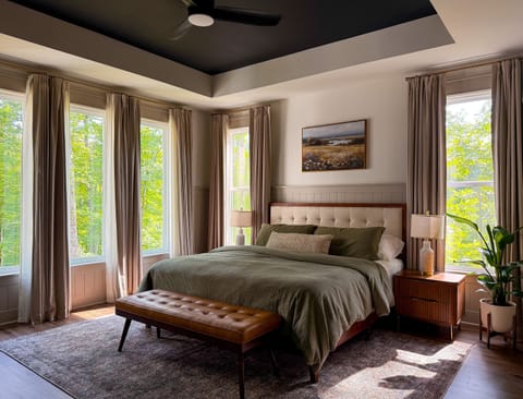 Sunlit primary bedroom with forest views and stylish, cozy finishes