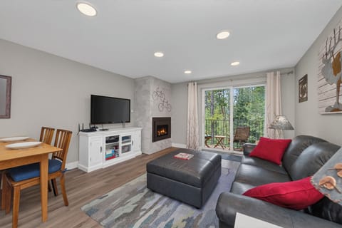 Unwind in your inviting living space with cozy fireplace, modern entertainment setup, and private balcony access offering serene garden views. Perfect for relaxing evenings at home.