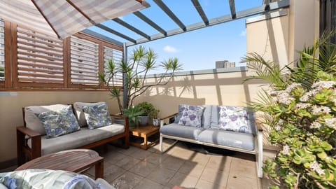 Relax outdoors on your private terrace, complete with comfortable lounge seating surrounded by lush greenery.