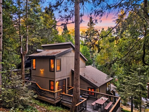 Woodland retreat tucked among the trees with wraparound decks and a peaceful sunset backdrop.