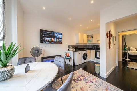 Open-plan living with marble dining table, smart TV and cosy fireplace glow