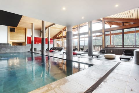 The indoor pool catches the light from the surrounding Alpine peaks — open December to April for guests looking to recover between ski days.