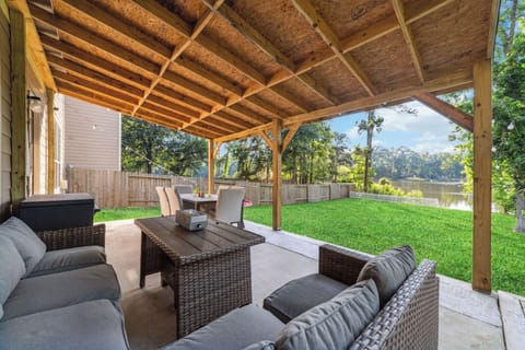 Covered patio with lounge seating, fenced yard, and serene waterfront views