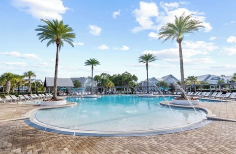 Resort-style pool with palm trees, loungers, and sunny tropical vibes