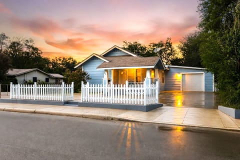 Charming cottage with white picket fence, porch, and glowing sunset curb appeal