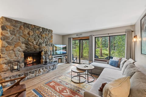 Curl up beside the crackling stone fireplace and unwind in your cozy retreat, where forest views through floor-to-ceiling windows bring nature right to your doorstep.