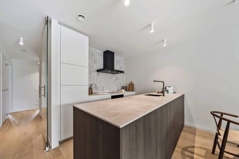 Sleek fully equipped kitchen with a central island, breakfast bar and modern appliances in this luxury holiday apartment in De Haan, perfect for self-catering stays near the North Sea beach on the Belgian coast.