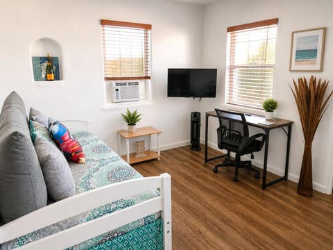 Sunny studio with daybed, workspace, AC, and smart TV—perfect WFH stay