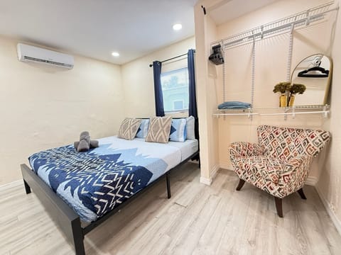 Cozy bedroom with mini-split AC, open closet, and stylish seating