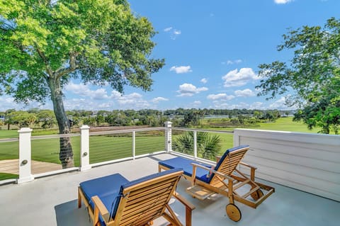Overlooks an expansive golf course with mature trees and open fairways, framed by a private balcony with lounge seating ideal for morning coffee or sunset cocktails.