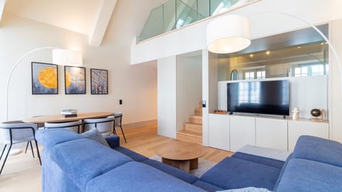 Discover a beautifully integrated living space that flows seamlessly from a comfortable lounge to a sophisticated dining area, offering ample room for socializing and relaxation. A modern wooden staircase gracefully leads to the private loft bedroom.