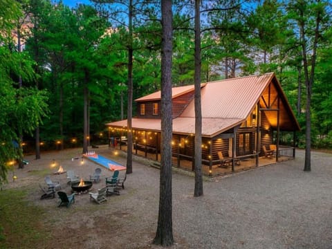The cabin comes alive at night with warm lighting, peaceful surroundings, and inviting outdoor gathering spaces.
