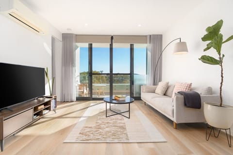 Stretch out on the comfy lounge and relax in this light-filled living space, complete with a Smart TV and seamless access to the balcony.