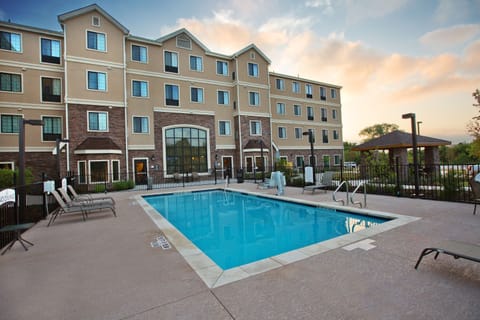 Outdoor swimming pool with lounge chairs, pool ladder, and gazebo in the background.