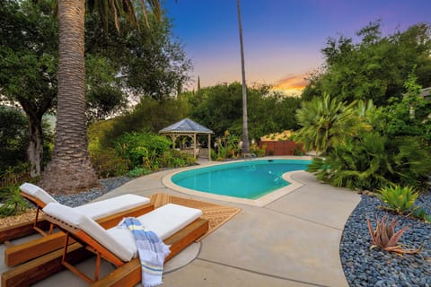 Sunny poolside retreat with lounge chairs, lush landscaping, and a peaceful hillside setting.