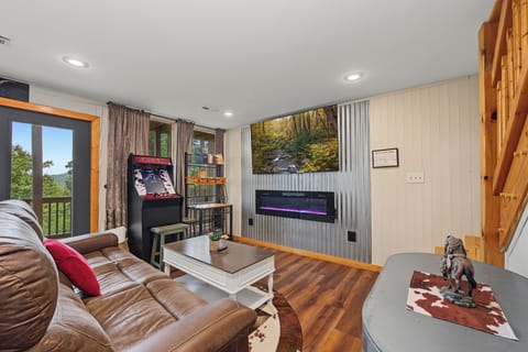 Unwind in your cozy living space with mountain views, an arcade, and modern fireplace—your perfect retreat for fun and relaxation.