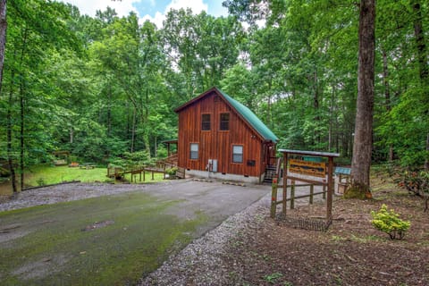 A charming cabin nestled in lush forest surroundings, featuring warm wood siding and ample parking, with a welcoming property sign marking your arrival to this serene woodland retreat.