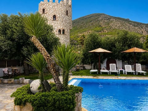 A peaceful poolside corner with palm plants, loungers, and mountain views. It feels private, sunny, and made for slow holiday afternoons