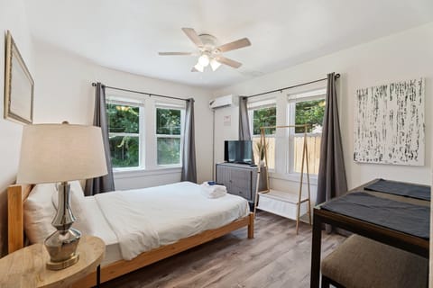 Bedroom — queen bed, wall-mounted smart TV.