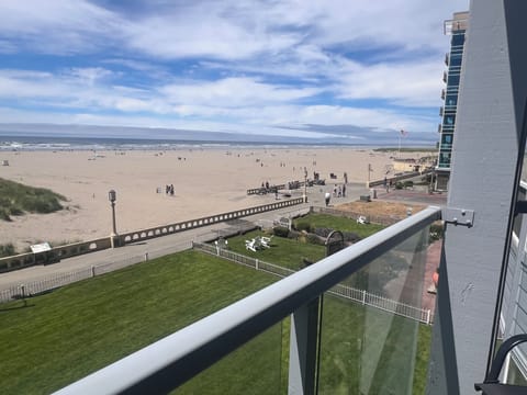 Beachfront property with direct beach access, offering a spacious sandy shore, green lawn area, and convenient walkways leading to the water's edge.