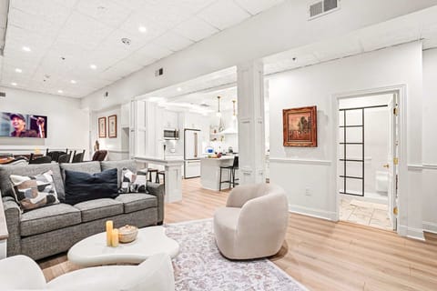Relax in style in this bright living area, featuring a plush sofa, cozy swivel chairs, and a mounted TV, all open to the sleek white kitchen. Perfect for movie nights or casual conversation.