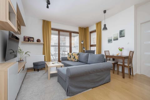 Bright and cozy living area with a comfortable sofa, dining table, and large windows leading to the balcony.