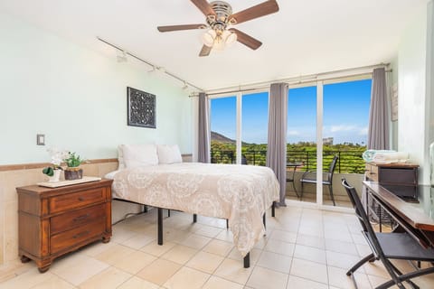 Wake up in your serene bedroom where a ceiling fan keeps you cool and floor-to-ceiling doors open to your private balcony, offering breathtaking mountain and ocean views to start your day.