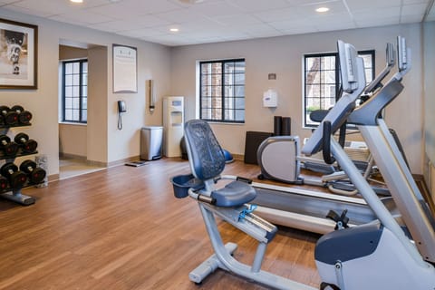 Fitness room showcasing cardio machines and selection of dumbbells.