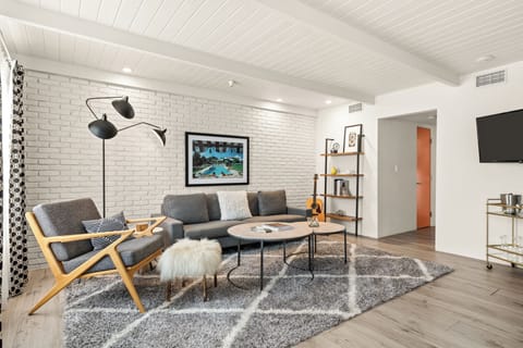 Stylish living room with mid-century seating, a textured brick wall, and a bright, modern feel.