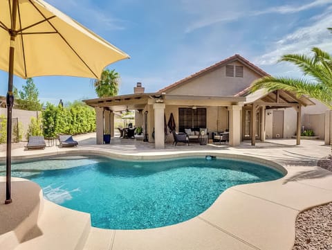 Private backyard pool with shaded lounge seating, covered outdoor living space, and a sunny desert feel.