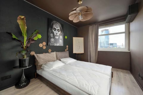 Stylish bedroom with a comfortable double bed, elegant wall art, and a large window filling the room with natural light.