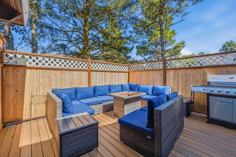 Unwind in your private deck with plush blue seating and a gas grill, perfect for outdoor meals beneath the pines under clear blue skies.